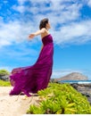 Teen girl in purple dress enjoying breeze on Hawaiian coast