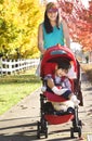 Teen girl pushing disabled little boy in red stroller outdoors