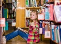 Teen girl reading a book on the floor in the library and showing thumbs up Royalty Free Stock Photo