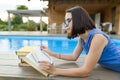 Teen girl reading book, girl alone in private area near the house and pool Royalty Free Stock Photo