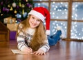 Teen girl in red christmas hat writes letter to Santa Claus Royalty Free Stock Photo