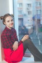 Teen girl in red skirt sitting on window sill