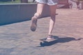 Teen girl rides on a skateboard in a city park. Female legs in sneakers closeup. Bright vintage photo Royalty Free Stock Photo