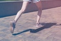 Teen girl rides on a skateboard in a city park. Female legs in sneakers closeup. Bright vintage photo Royalty Free Stock Photo
