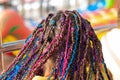 Teen girl`s hair with small afro pigtails with bright multicolored ribbons