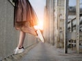 Teen girl`s legs in white sneakers on the bridge at sunset Royalty Free Stock Photo