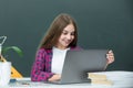 Teen girl school student with laptop at school. Teenager Student Working On Laptop in classroom. Little girl using Royalty Free Stock Photo