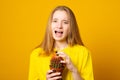 Teen girl screams in pain, pricked by a cactus on a yellow background. Stress and health concept