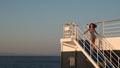 Teen girl in shorts standing on top of blue stairway on ferry boat Royalty Free Stock Photo