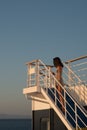 Teen girl in shorts standing on top of blue stairway on ferry boat Royalty Free Stock Photo