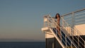 Teen girl in shorts standing on top of blue stairway on ferry boat Royalty Free Stock Photo