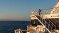 Teen girl in shorts standing on top of blue stairway on ferry boat Royalty Free Stock Photo