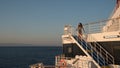 Teen girl in shorts standing on top of blue stairway on ferry boat