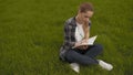 Teen girl sits on the grass and takes notes in a notebook. teen girl sits on the grass and takes notes in a notebook. 4K