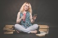 Teen girl sitting on the floor next to books, does not want to learn, drinking juice and taking a selfie on the smartphone