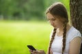 Teen girl sitting near tree with mobile phone Royalty Free Stock Photo