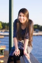 Teen girl sitting on railing overlooking lake Royalty Free Stock Photo