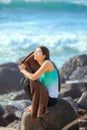 Teen girl sitting on rocky beach shore drying off Royalty Free Stock Photo