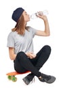 Teen girl sitting on skate board drinking water Royalty Free Stock Photo