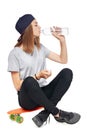 Teen girl sitting on skate board drinking water Royalty Free Stock Photo