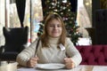 Teen girl sitting at a table in a festive cafe waiting for a delicious dinner