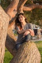 Teen girl sitting on tree branch by lake at sunset Royalty Free Stock Photo