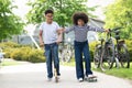 Teen girl on skateboard and boy on scooter having fun on sunny day, relaxation, sports lifestyle. Royalty Free Stock Photo