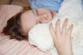 Teen girl sleeping in an embrace with a white teddy bear in bed Royalty Free Stock Photo