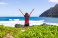 Teen girl raising arms in praise standing by ocean shore