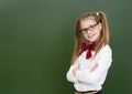 Teen girl standing near empty green chalkboard. Space for text