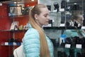 Teen girl standing near showcase with photo cameras