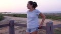 Teen girl standing on walkway by the sea and looking aside