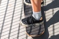 Teen girl stands on a skateboard. The photo shows a skate and black sneakers Royalty Free Stock Photo