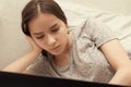 Teen girl studying at home, lies with a laptop in bed, performs tasks