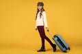 teen girl with suitcase for trip on yellow background, adventure