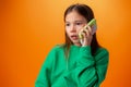 Teen girl talking on cell phone isolated on orange background Royalty Free Stock Photo