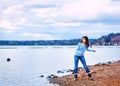 Teen girl throwing rocks in the water, along a rocky lake shore