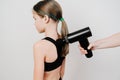 Teen girl uses a massage gun. medical-sports device