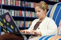 Teen Girl using Laptop in Library and Relaxing in Bean Bag Royalty Free Stock Photo