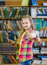 Teen girl using a tablet computer in a library and showing thumbs up Royalty Free Stock Photo