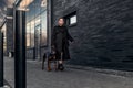 Teen girl walking down the street with her doberman. Great view. Full length of a beautiful young girl in a black cloak. Security Royalty Free Stock Photo