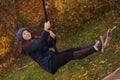 Teen girl in warm woolen gaiters half hose swinging in the autumn city park Royalty Free Stock Photo