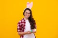 Teen girl wearing bunny ears and hold colorful painted easter eggs isolated at yellow background. Happy teenager Royalty Free Stock Photo