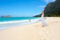 Teen girl in white dress on Hawaiian beack, arms raised