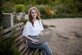 Teen girl working on a laptop seated sitting on a bench in the park, looking and smiling at camera in day time Royalty Free Stock Photo