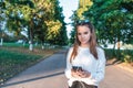 Teen girl 12-15 years old portrait, summer city, hand of smartphone, listens music with headphones, outdoor recreation Royalty Free Stock Photo