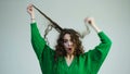 Teen hair moving. Curly girl with braces in a green sweater pulls hair. The concept of hair care. Excited tennager girl