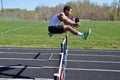 Teen jumping hurdle in a track and field event