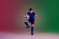 Teen male football or soccer player, boy on gradient background in neon light - motion, action, activity concept Royalty Free Stock Photo