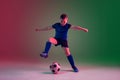 Teen male football or soccer player, boy on gradient background in neon light - motion, action, activity concept Royalty Free Stock Photo